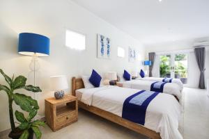 2 camas en una habitación blanca con detalles azules en Villa Marronniers en Seminyak