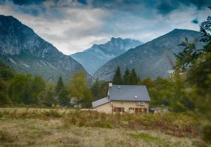 una casa en un campo con montañas en el fondo en Gite Ballestan, en Saint-Béat