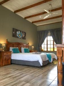 een slaapkamer met een groot bed met blauwe kussens bij Hendersons Lodge Ltd in Senekal