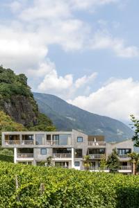 an apartment building with a mountain in the background at Boutique-Hotel Ballguthof am Golfplatz in Lana