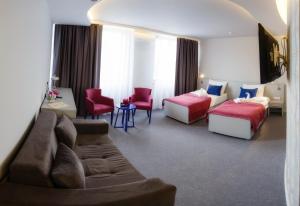 a hotel room with two beds and a couch at Hotel Kragujevac in Kragujevac