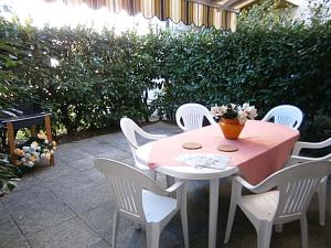 a pink table with white chairs and a vase of flowers on it at Capri in Bibione