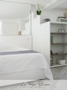 een slaapkamer met een wit bed en witte planken bij La Porta Bianca in Trieste