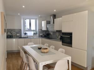 a white kitchen with a white table and chairs at L'écrin de Masevaux in Masevaux