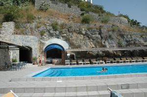 a person swimming in a swimming pool next to a mountain at Hotel Belvedere in Conca dei Marini
