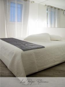 een wit bed met witte lakens en kussens bij La Porta Bianca in Trieste