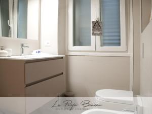 a bathroom with a toilet and a sink and a window at La Porta Bianca in Trieste