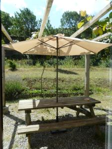 - une table de pique-nique avec un parasol dans la cour dans l'établissement Bergerie Du Plo, à Montlaur