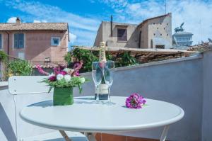 a table with a wine glass and flowers on a balcony at Margana Tower in Rome