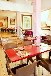 un restaurante con mesa roja, sillas y mesas en Brooklyn Lodge, en Pretoria