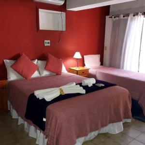 two beds in a room with red walls at Petit Hotel Caraguata in Puerto Iguazú