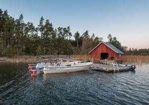 a boat is docked at a dock with a red barn at Finn&ouml; Stugby in Geta