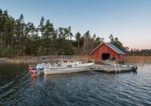 a boat is docked at a dock with a red barn at Finnö Stugby in Geta