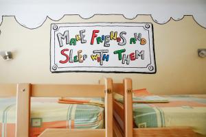 a sign on a wall above two bunk beds at City Hostel in Novi Sad