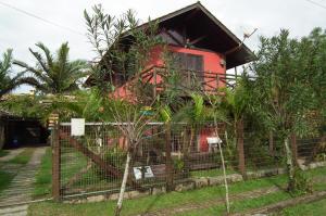 una casa con un camión rojo detrás de una valla en Cabanas Aconchegantes próximas ao mar, en Garopaba