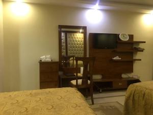 - une chambre avec un lit, une télévision et une chaise dans l'établissement Hotel Shalimar Rawalpindi, à Rawalpindi