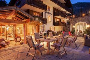 a patio with a wooden table and chairs at Hotel Berghof in Zermatt
