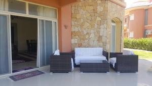 a patio with wicker furniture and a stone wall at Stand alone Villa at Blumar North coast -SIDI ABD ALRAHMAN in El Alamein