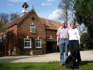 a man and a woman standing in front of a building with a dog at Brackenborough Hall Coach House - Stables in Louth