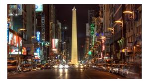 a city street at night with a tall building at Dg Apart Obelisco in Buenos Aires