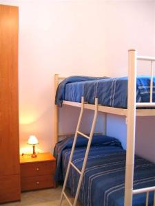 サン・ヴィート・ロ・カーポにあるBluvacanze Appartamento Stellaのベッドルーム1室(二段ベッド2台、ランプ付きテーブル付)