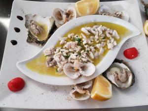 a plate with a bowl of seafood soup with oysters at Blue Paradise Hotel in Orikum