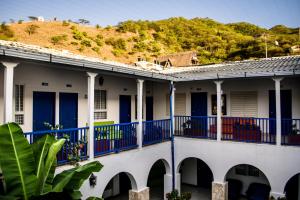 una casa con balcones azules y una colina en el fondo en La Ballena Azul Hotel, en Taganga