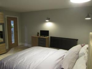 a bedroom with a white bed and a television at The Apartment, Lower Ground Floor, Clarendon Place in Leamington Spa