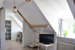 een woonkamer met een tv en een trap bij B&B Villa Bon Papa in De Panne