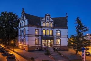 ein großes weißes Gebäude mit nachts eingeschaltetem Licht in der Unterkunft Stadtperle Rostock in Rostock
