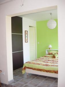 Les TailladesにあるGite des Tailladesの緑の壁、ベッド付きのベッドルーム1室