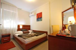 1 dormitorio con cama y escritorio con espejo en Guesthouse Villa Inn, en Subotica