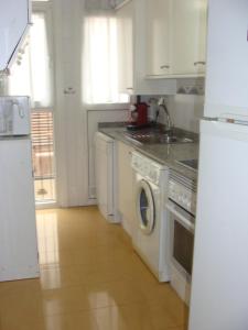 cocina blanca con fogones y lavavajillas en Apartamento Torres, en Valencia