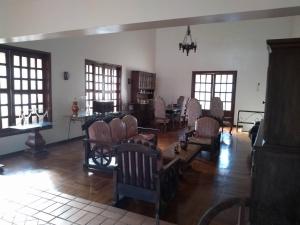 a living room with chairs and a table and windows at Casa Temporada Vila Residencial Furnas, Capitólio MG in Furnas