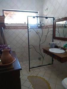 a bathroom with a shower with a sink and a mirror at Casa Temporada Vila Residencial Furnas, Capitólio MG in Furnas