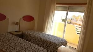 - une chambre avec 2 lits et une grande fenêtre dans l'établissement Terraços Vista Mar Royal Cabanas, à Cabanas de Tavira