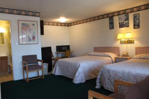 a hotel room with two beds and a chair at Century 21 Motel in Las Cruces