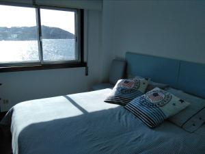 a bedroom with a bed with two pillows and a window at Primera linea. Vistas al MAR in A Coruña