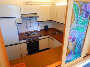 a small kitchen with white cabinets and a stained glass window at "Gletscherblick" in Bad Aussee