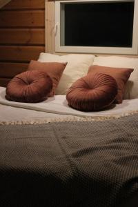 Una cama con dos almohadas marrones encima. en Villa Orohat 1, en Rovaniemi