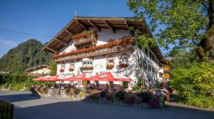 a building with red umbrellas in front of it at Postgasthof Fischerwirt in Walchsee