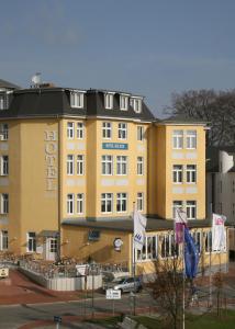 ein großes gelbes Gebäude mit Flaggen davor in der Unterkunft Hotel See-Eck in Heringsdorf