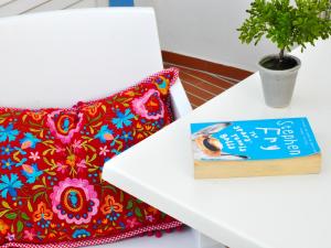 a pillow and a book on a table with a plant at Patios Da Vila Boutique Apartments by AC Hospitality Management in Vila Nova de Milfontes