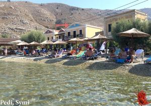 a group of people sitting on the shore of a body of water at Korali in Symi