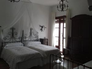 Hacienda Olontigi في Aznalcázar: غرفة نوم بسرير ونافذة وثريا