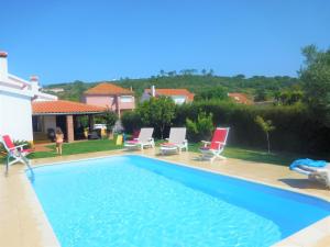 a swimming pool with chairs and a house at Casa AMOReira de Óbidos in Amoreira