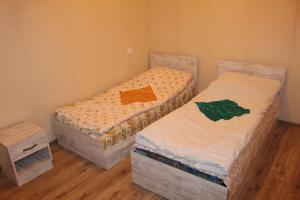 two twin beds in a room with wooden floors at Guest House Daviti in Zestafoni