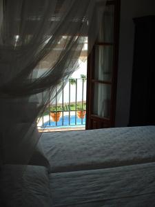 1 dormitorio con cama y vistas a la piscina en Hacienda Olontigi en Aznalcázar