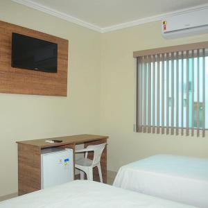 a hotel room with a desk and a tv at Planalto Palace Hotel in Rurópolis