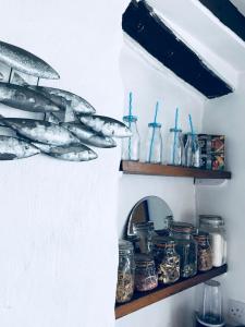 uno scaffale pieno di pesci e barattoli su un muro di Cobb Cottage a Bovey Tracey